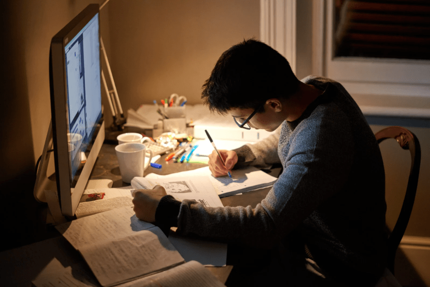 Un joven estudiando de noche en su escritorio.